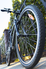Grey sport trail bike on the street closeup near green bushes. Selective focus on wheel center.