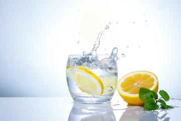 Fototapeta na wymiar yellow lemons in a glass and splashes of water. Tasty and healthy food. Seasonal drinks