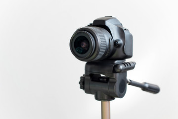 Professional black DSLR mirrorless camera on tripod on white background. Blogging and video recording or photo shooting.