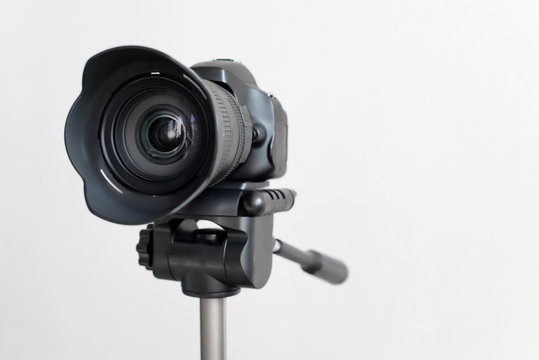 Professional black DSLR mirrorless camera on tripod on white background. Blogging and video recording or photo shooting.