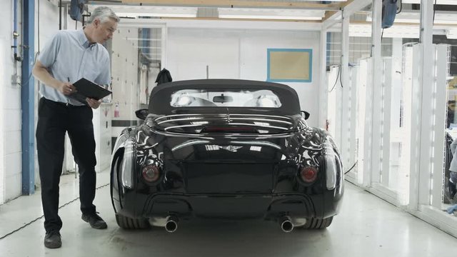 Car manufacturing plant engineers working on vehicles