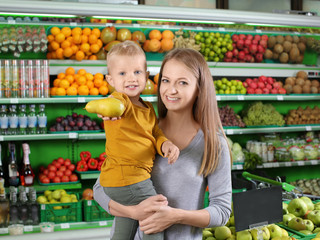 Fototapeta na wymiar Young mother with little son choosing food in supermarket