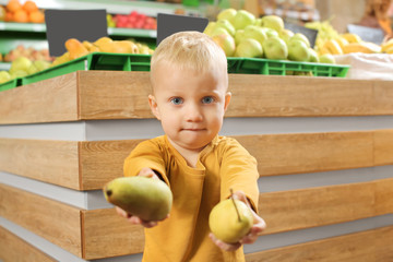 Fototapeta premium Cute little boy choosing pears in supermarket