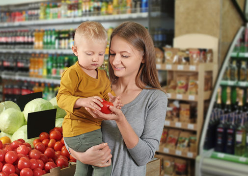 Young mother with little son choosing food in supermarket
