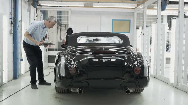 Car manufacturing plant engineers working on vehicles