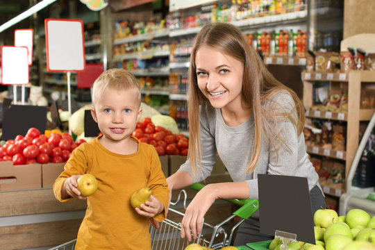 Young mother with little son choosing pears in supermarket