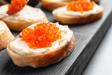 Delicious sandwich with red caviar on wooden board, closeup