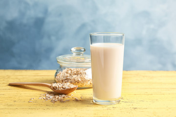Glass with oat milk and flakes on wooden table