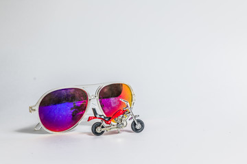 sunglasses with red toy motorcycle on white background