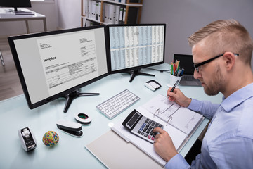 Fototapeta na wymiar Side View Of A Businessman Calculating Invoice