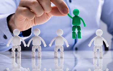 Person Selecting Green Figure Amongst White Human Figures