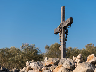Rosary hanging on a small wooden cross on a stone wall