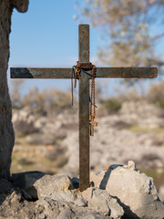 Fototapeta premium Rosary hanging on a small iron cross on a stone wall