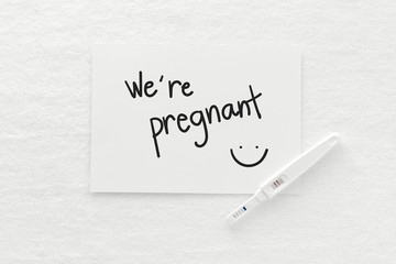 Message "we're pregnant"  written on paper