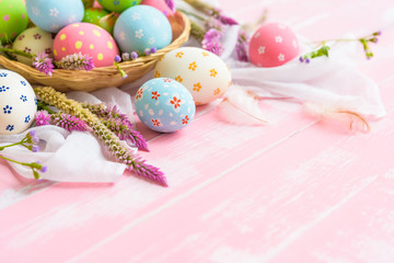 Happy easter! Colorful of Easter eggs in nest with paper star, flower and Feather on pastel color bright pink and white wooden background.