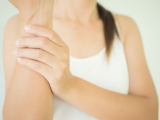 Close up young woman holding her wrist symptomatic Office Syndrome. Healthcare and arm pain concept.