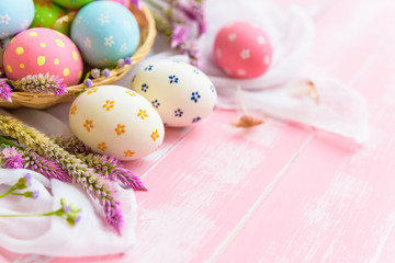 Happy easter! Colorful of Easter eggs in nest with paper star, flower and Feather on pastel color bright pink and white wooden background.