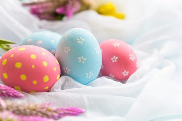Happy easter! Colorful of Easter eggs in nest with flower,  paper star and Feather on white cheesecloth background.