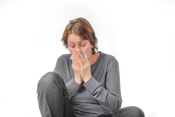 woman with closed eyes sneezes into napkin