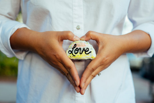 A young woman holding a small rock that says "love"