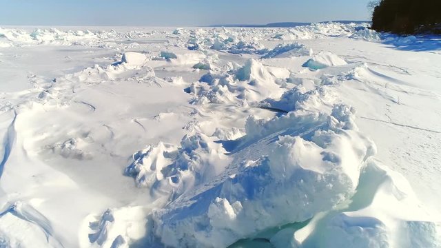 Low aerial flight over scenic, surreal jagged ice shoves on the shore of Door County Wisconsin, created by high winds in Springtime.