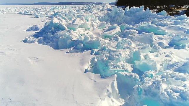 Low aerial flight over scenic, surreal jagged ice shoves on the shore of Door County Wisconsin, created by high winds in Springtime.
