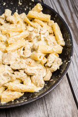 Creamy pasta with chicken and mozzarella cheese in pan. Selective focus.