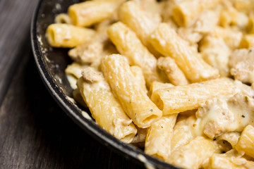 Creamy pasta with chicken and mozzarella cheese in pan. Selective focus.