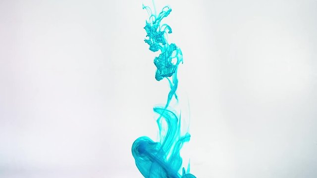 The flow of ink in water on white background. Colour ink in water creating an abstract cloud forms, close-up view.