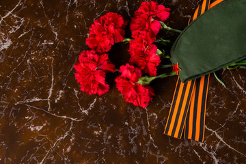 5 carnations, military cap and St. George ribbon, against the background of marble