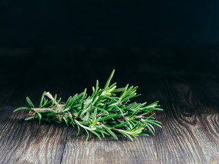 Organic bunch of fresh rosemary on wooden table with copy space. Low key