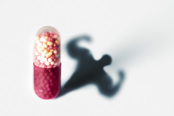 Sports doping, anabolic capsule - shape of a male muscular upper body - symbol for medical drug...