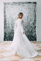Fototapeta premium Beautiful young bride in boudoir dress on canvas background with paint. Wedding trends and ideas 2018, spring inspiration. Wedding in the Studio