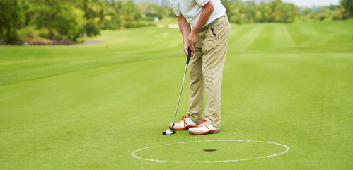 Obraz premium Asian golfer putting on green in summer vacation