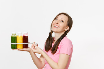 Woman holds row of green, red, yellow detox smoothies in bottles, measure tape isolated on white background. Proper nutrition, vegetarian drink, healthy lifestyle, dieting concept. Copy space, flack.