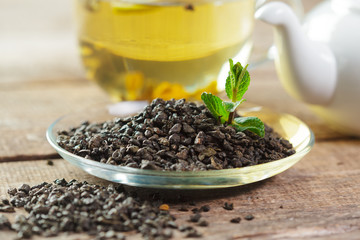cup of black tea with mint leaves on a wooden table