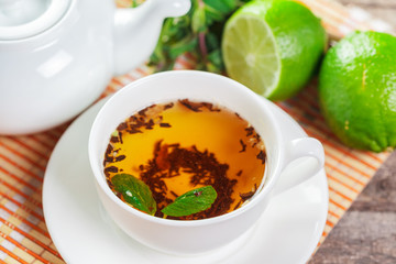 cup of black tea with mint leaves on a wooden table