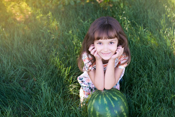 Large striped watermelon. Little sweet girl. Juicy green grass. Summer landscape