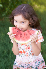Little beautiful girl. Bright green grass. Juicy, delicious, red watermelon