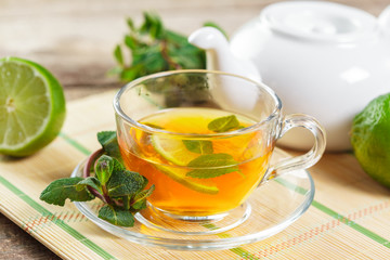 cup of black tea with mint leaves on a wooden table