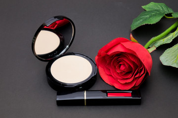 Obraz na płótnie Canvas Flowers rose,Powder and lipstick brush uses lips on black background