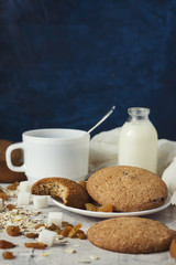 Cup of black coffee in a white cup, Bottles with milk, oatmeal cookies, oatmeal, raisins on a light...
