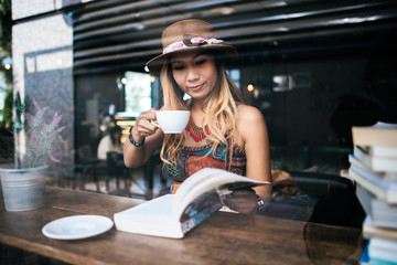 Fototapeta na wymiar woman is holding a cup of hot cappuccino and reading a book, Business woman read a book in coffee shop