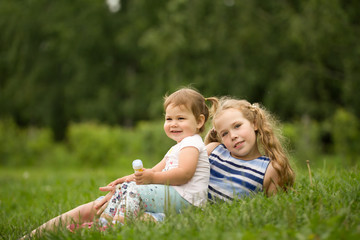 A two babies sisters playing in park, outdoor portrait