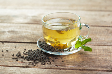 cup of black tea with mint leaves on a wooden table