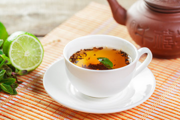 cup of black tea with mint leaves on a wooden table