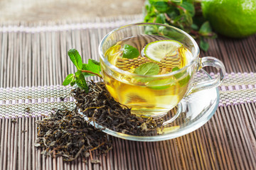 cup of black tea with mint leaves on a wooden table