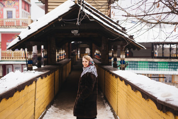A young beautiful girl in a mink coat and a Russian folk scarf walks around the Izmailovo Kremlin. Moscow, Russia.