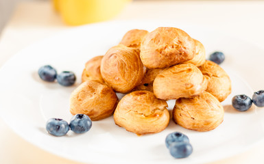 Homemade profiteroles served with blueberries on a white plate