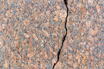 Red granite slab with a deep crack. Natural stone texture